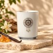 Mahonie Amber and Vanilla Candle, white glass, on pale natural stone.