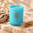 Mahonie Beachwood Vetiver and Driftwood Candle, turquoise glass, on pale natural stone.