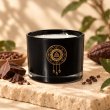 Mahonie Choco Lava Candle, black glass, on pale natural stone.