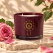 Mahonie Damask Rose Candle, burgundy glass, on pale natural stone.