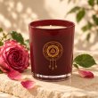 Mahonie Damask Rose Candle, burgundy glass, on pale natural stone.