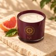 Mahonie Grape Fruit Candle, elevated view on pale natural stone.