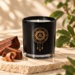 Mahonie Mahogany Scented Candle, black glass, on pale natural stone.