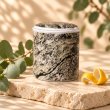 Mahonie Métallique : Citric Eucalyptus Candle, three-quarter view on pale natural stone.