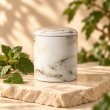 Mahonie Métallique : Exquisite Patchouli Candle, pale marble-pattern vessel, on pale natural stone.