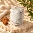 Mahonie Métallique : Silk & Satin Caramel Candle, elevated view on pale natural stone.