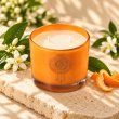 Mahonie Orange Blossom Candle, elevated view on pale natural stone.