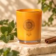 Mahonie Patchouli and Cinnamon Candle, orange glass, on pale natural stone.