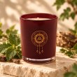 Mahonie Patchouli Candle, burgundy glass, on pale natural stone.