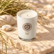 Mahonie Saltwater Sea Musk Candle, elevated view on pale natural stone.