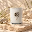 Mahonie Saltwater Sea Musk Candle, white glass, on pale natural stone.