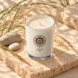 Mahonie Saltwater Sea Musk Candle, elevated view on pale natural stone.