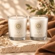 Mahonie Shot Glass Pair : Musk & Leather Candle, two clear shot glasses, on pale natural stone.