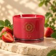 Mahonie Strawberry Candle, red glass, on pale natural stone.