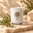 Mahonie Thyme candle, white glass, on pale natural stone.