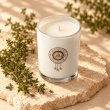 Mahonie Thyme candle, elevated view on pale natural stone.
