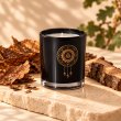 Mahonie Tobacco & Oakwood Candle, three-quarter view on pale natural stone.