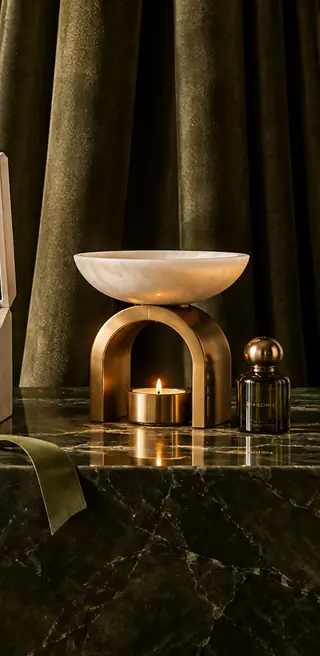 Brass aroma burner with a candle and fragrance bottle against olive curtains